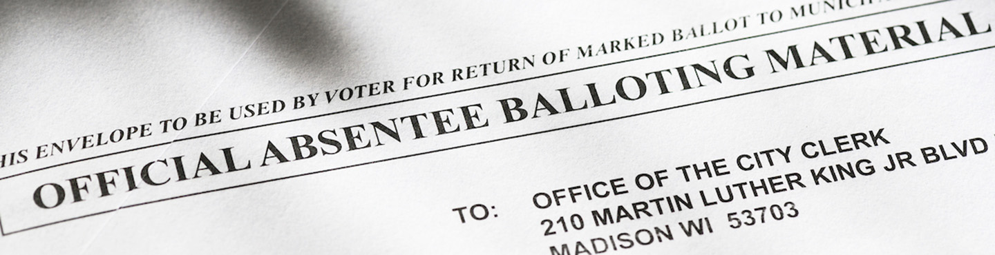 Cropped photo of an absentee mail-in ballot. Text reads Official absentee balloting material. Part of the city clerk's address is also visible.