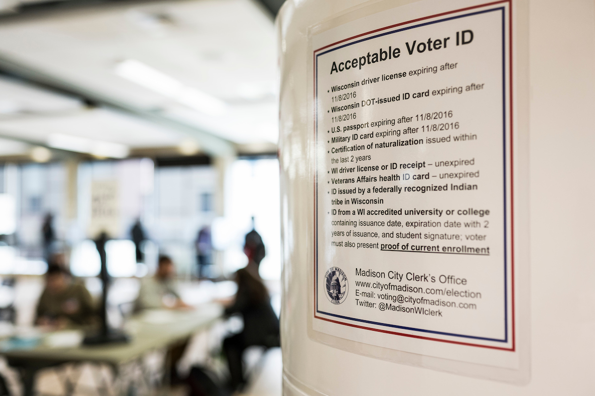 Photo of a sign posted to a wall displaying information about acceptable forms of voter identification.